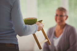 Caregiver bringing food tray to woman