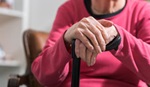 Photo of individual with hands resting on a cane